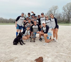 a photo of students playing softball with a trophy