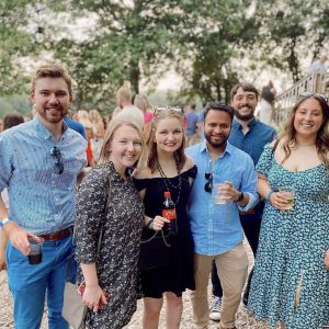 a photo of students outside at a party by the river