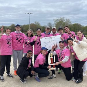 a photo of students after a softball game with a trophy